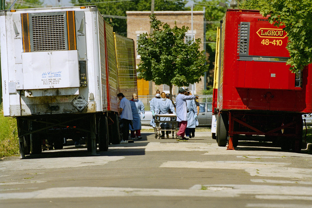 Cook County morgue technicians work between a row of refrigerated trucks outside the morgue on Tuesday, July 18, 1995, as the city of Chicago continues to deal with the rising death count from the recent heat wave to hit the area. At least 199 lives have been claimed by the hot humid temperatures. 